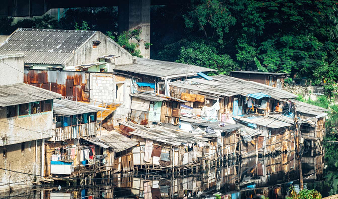 Slumgebiet in der Nähe eines verschmutzten Flusses unter einer Brücke. Viele Menschen in Jakarta leben in Slumgebieten, Armut ist eines der größten Probleme in der Stadt Jakarta.