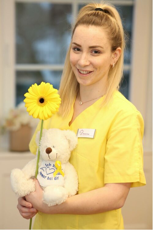 Melanie Vogt mit Teddy, Sonnenblume und gelber Schleife