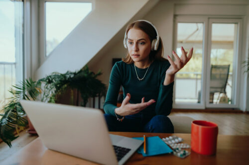 Junge Frau sitzt zu Hause im Wohnzimmer  hat eine Videoanruf-Online-Therapiesitzung  ihrem Therapeuten