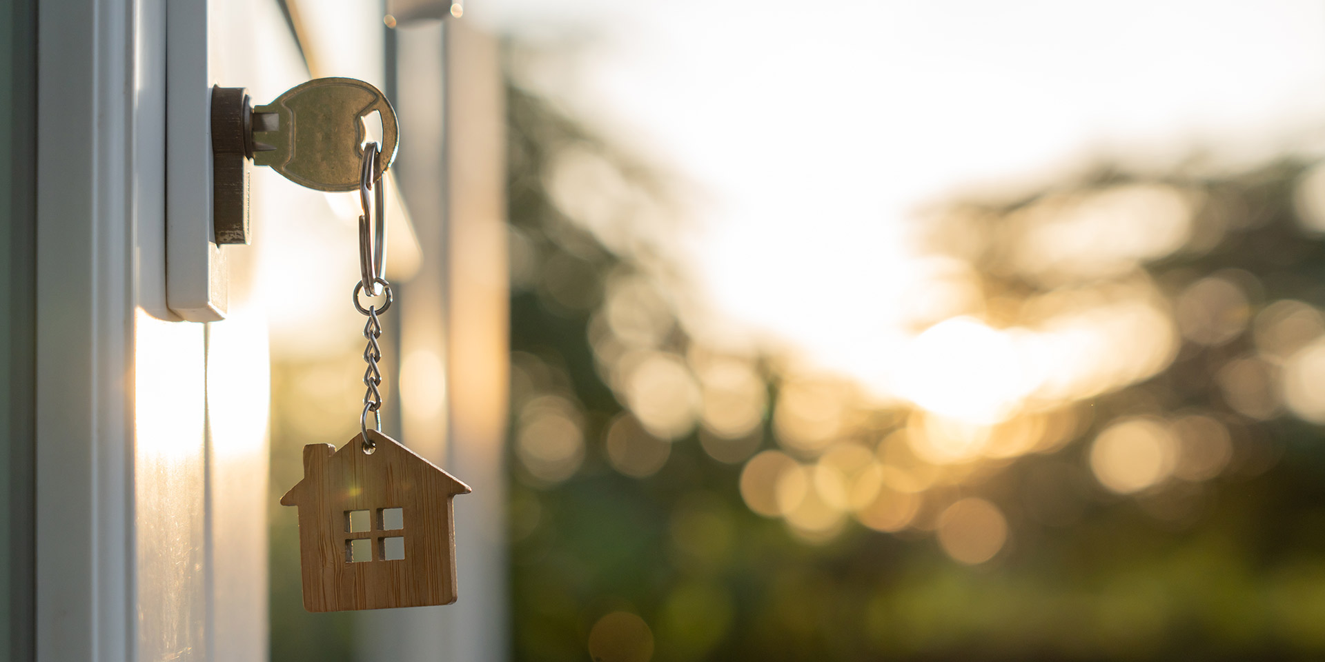 landlord key for unlocking house is plugged into the door. second hand house for rent and sale. keychain is blowing in the wind. mortgage for new home, buy, sell, renovate, investment, owner, estate