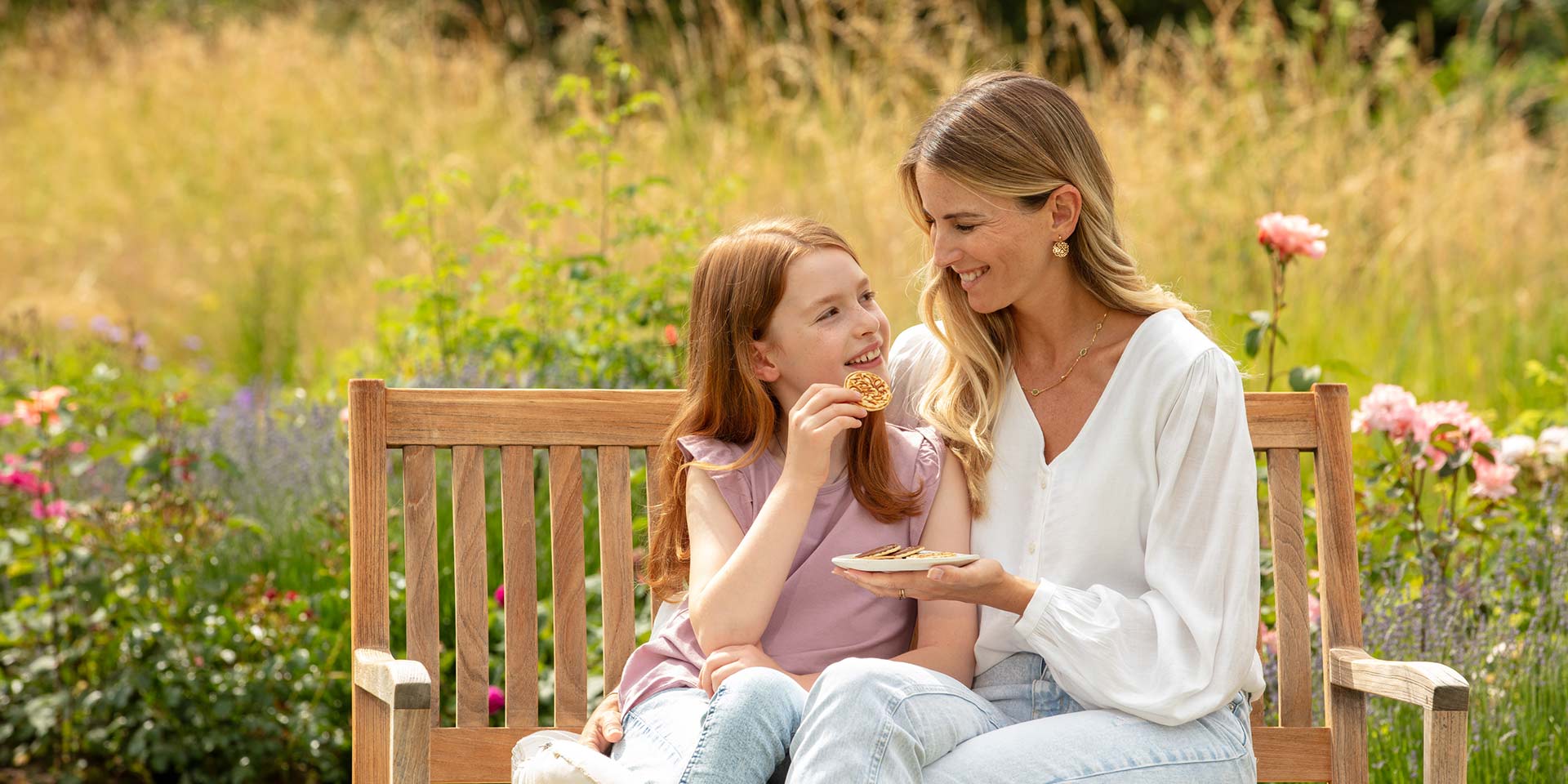 woman and child eating snacks on a bench