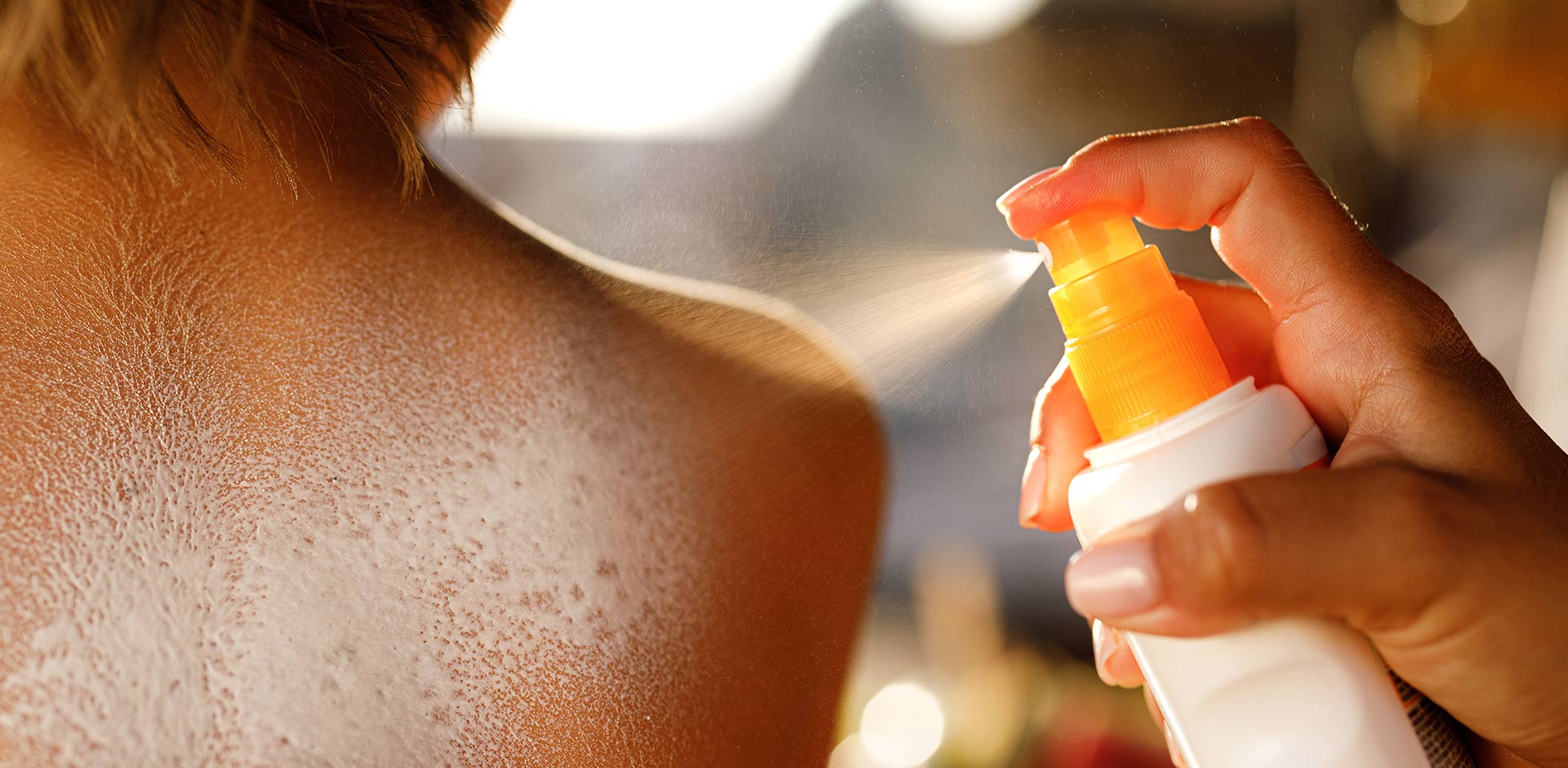 gros plan d'une mère méconnaissable vaporisant de la crème solaire sur le dos de son fils à la plage. il faut se protéger du soleil