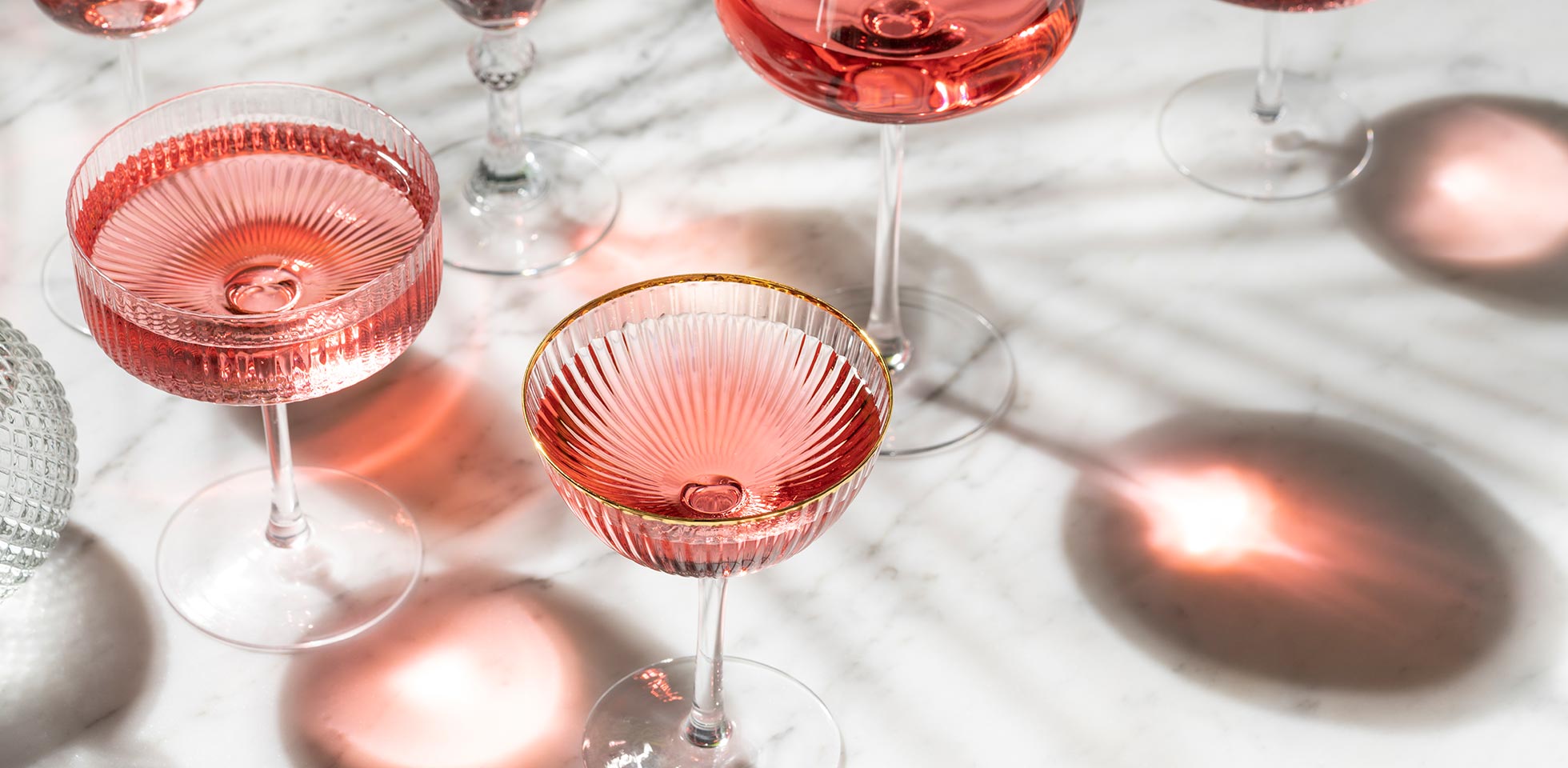 cocktail ou mocktail de roses avec lumière d'été ensoleillée sur table en marbre blanc et ombres de palmiers. vins et spiritueux