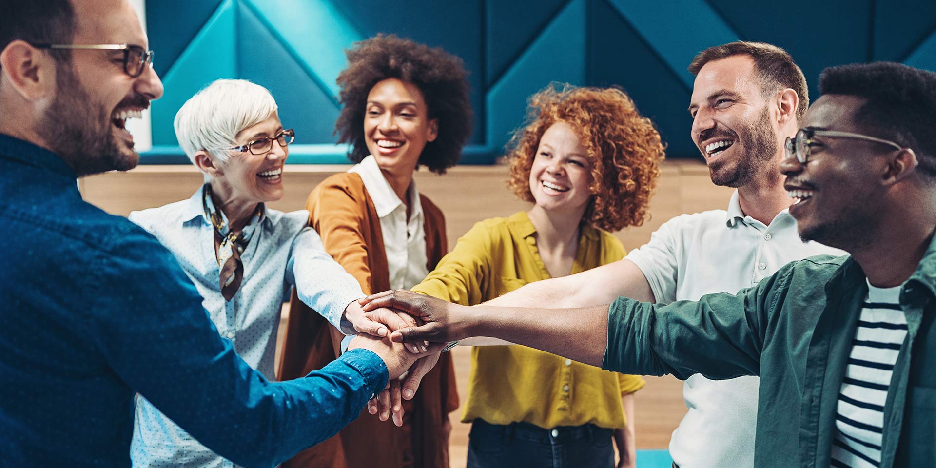 group of smiling business persons stacking hands