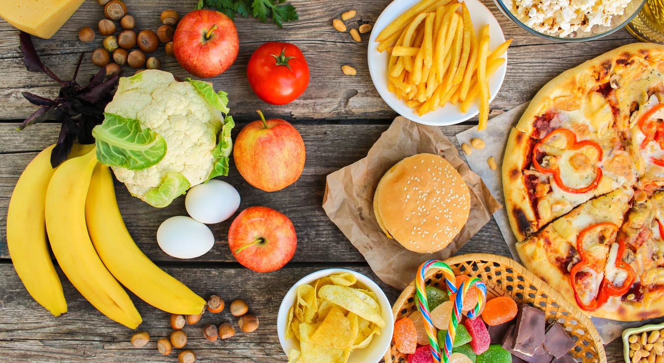 Fastfood und gesunde Ernährung vor altem Holzhintergrund. Konzept zur Auswahl der richtigen Ernährung oder Junkfood. Draufsicht.