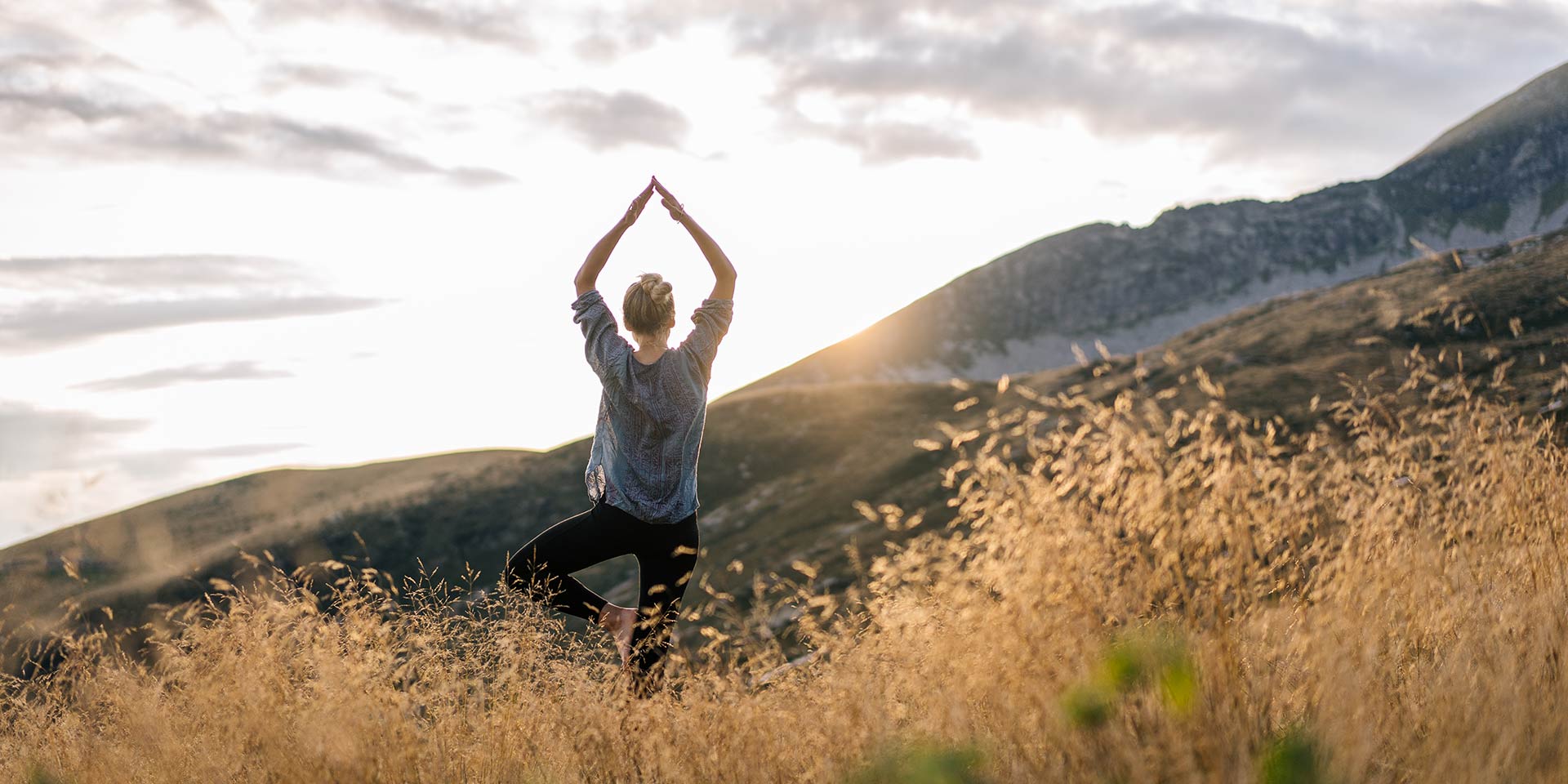 young man preforms yoga in mountains in morning light stock photo