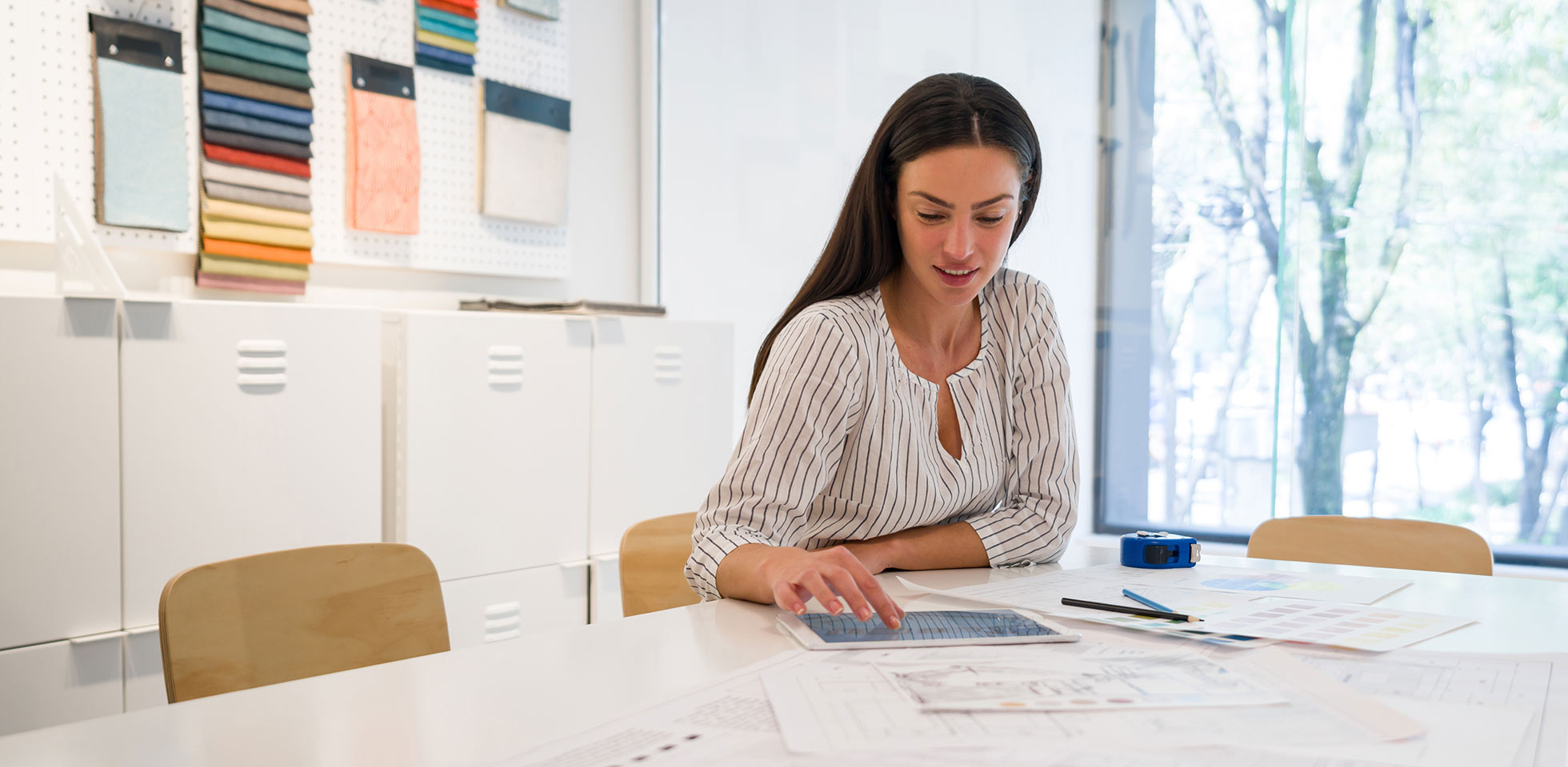 une décoratrice d'intérieur à succès regarde des photos sur sa tablette au bureau - concepts de professions créatives