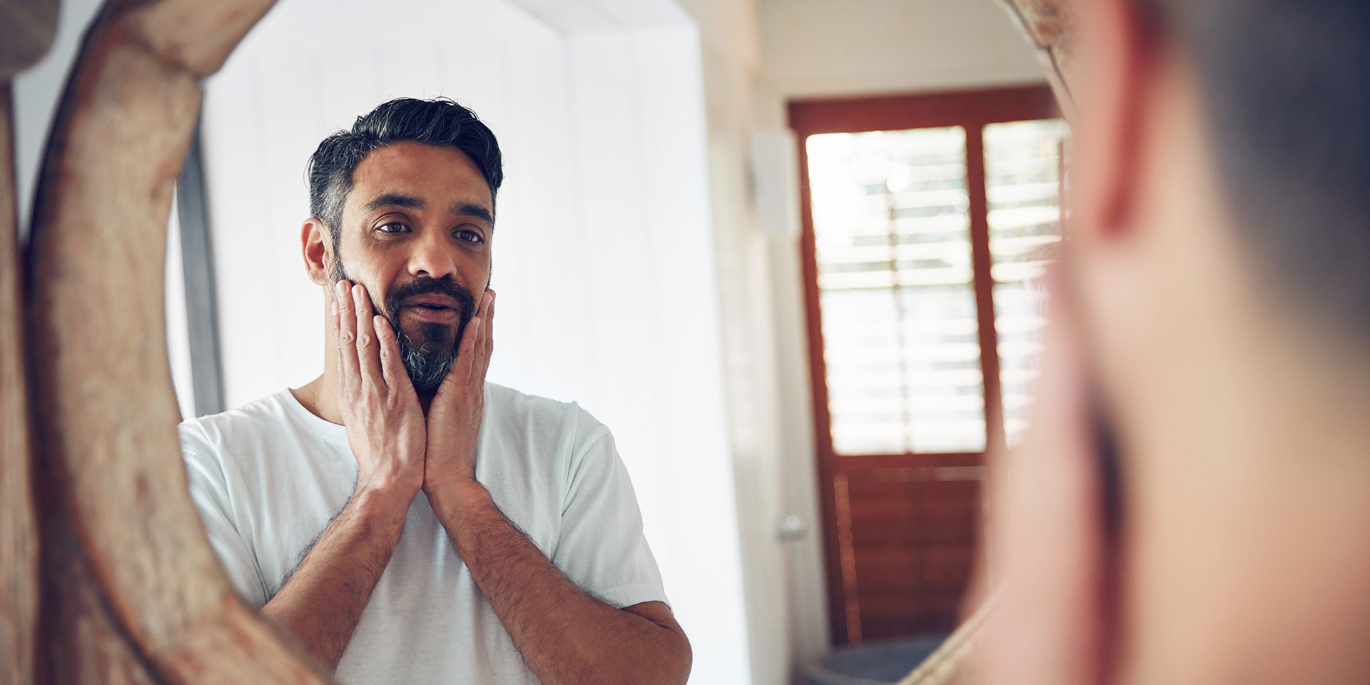 shot of a mature man looking at his reflection the bathroom mirror