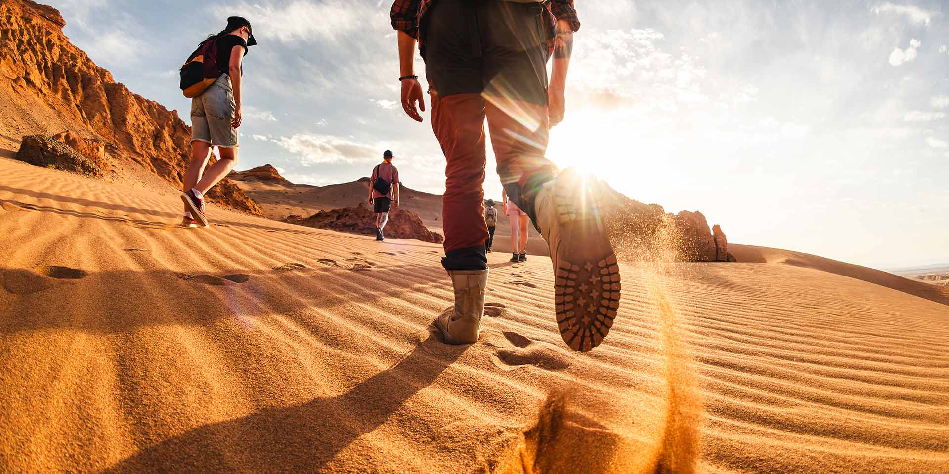 big group of young hikers or tourists with backpacks walks in sunset gobi desert