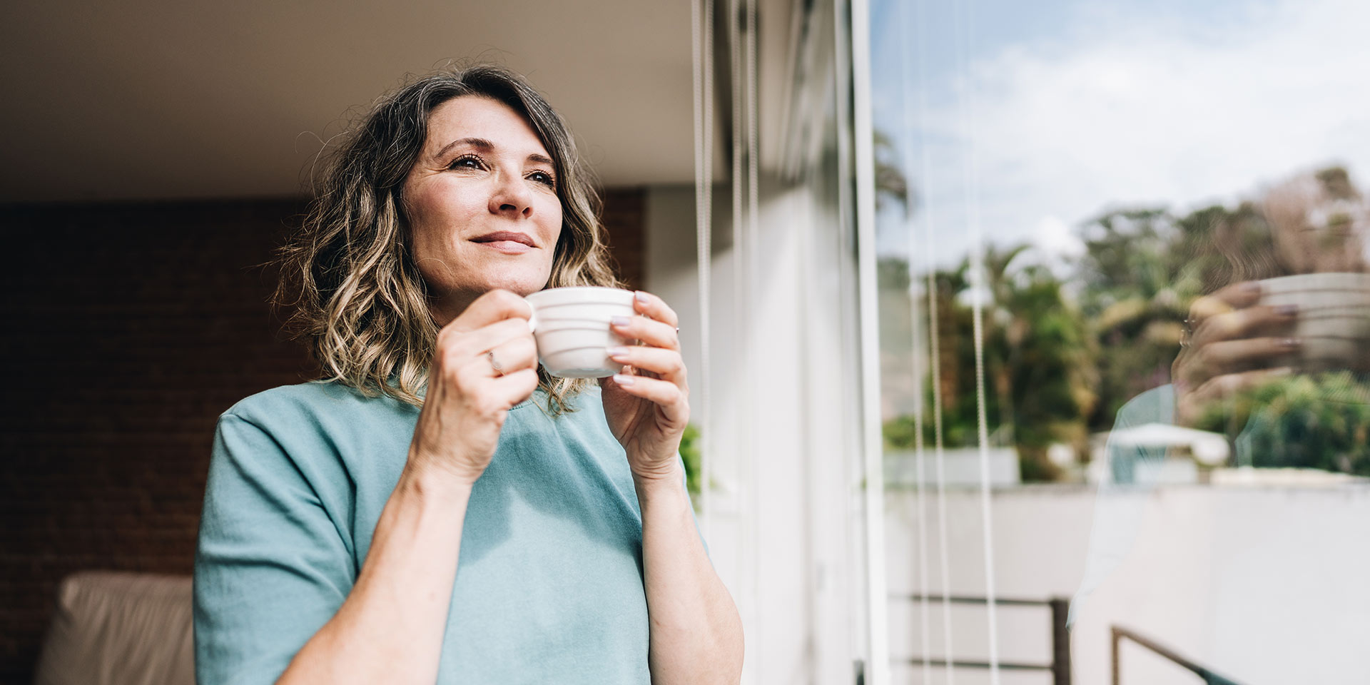contemplative mature man looking throught the window at home