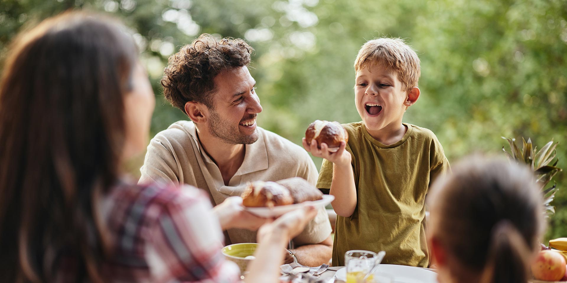 happy father and son having a meal with their family in nature