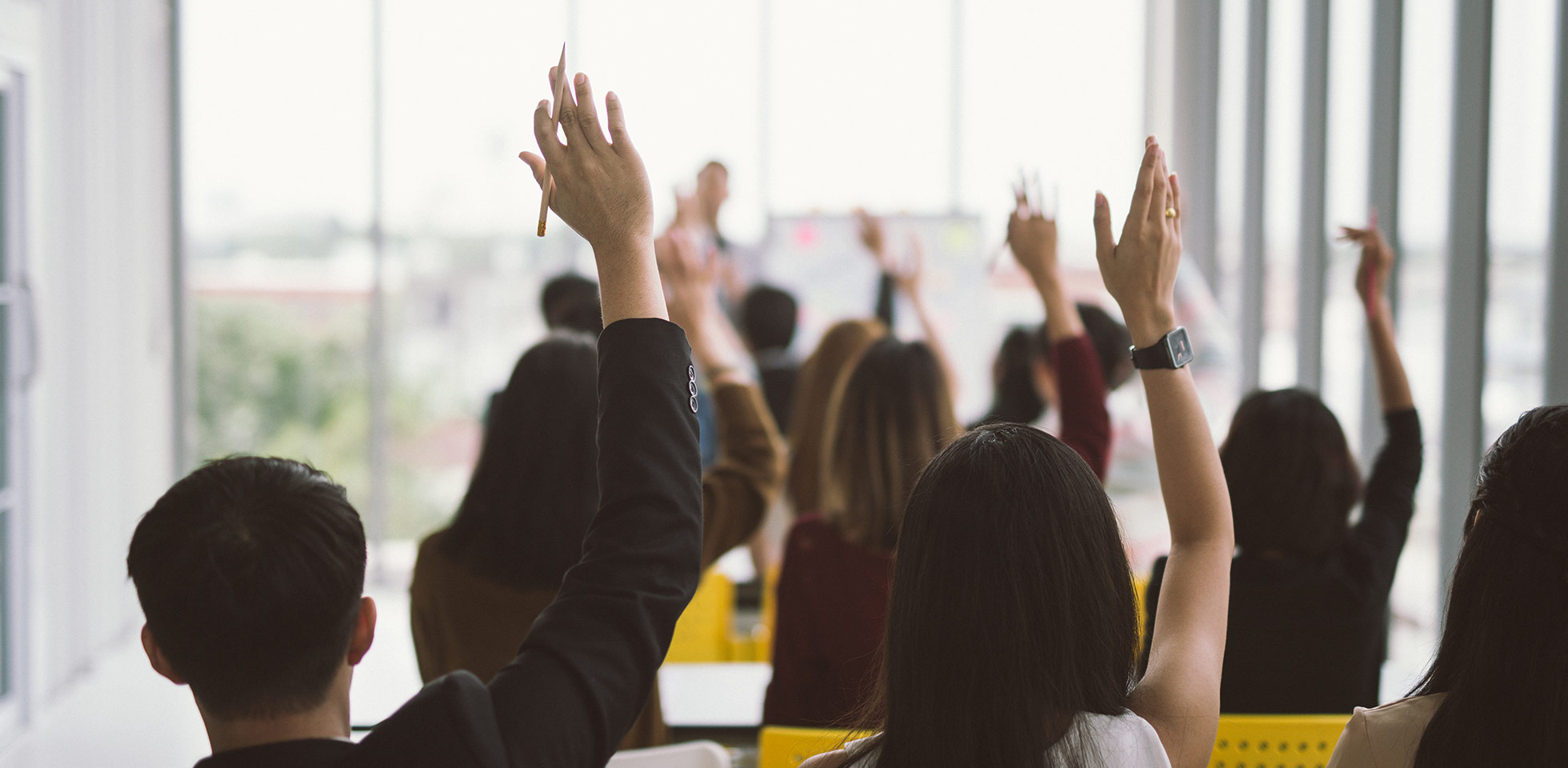 mains et bras levés d'un grand groupe dans une salle de séminaire lors d'une conférence