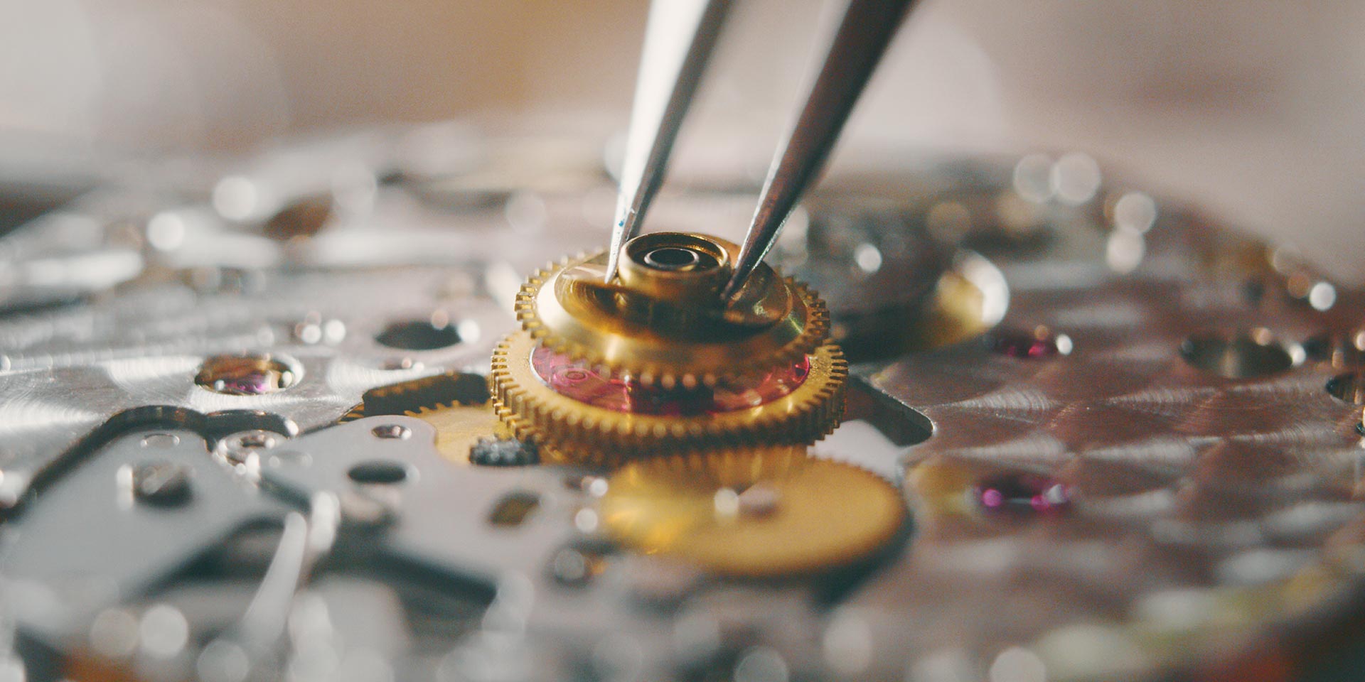 portrait close up of a professional watchmaker repairer rking on a vintage mechanism clock in a rkshop.